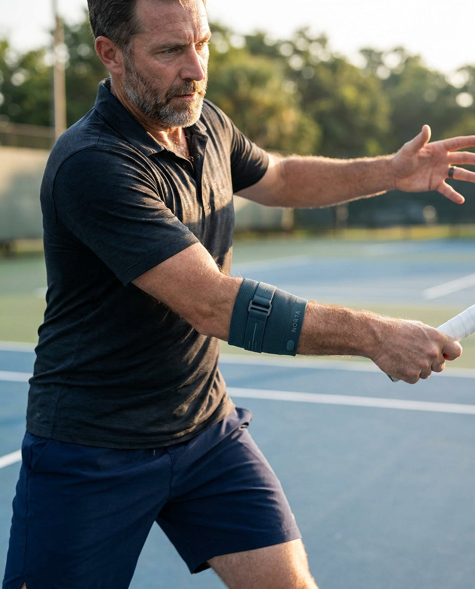 A tennis player in his fifties mid-forehand wearing the Norta band on his forearm